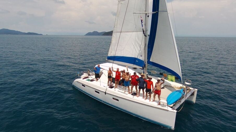 Gruppenfoto mit 9 Männern auf Segelboot auf offenem Wasser