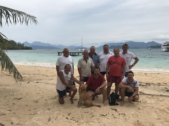 Gruppenfoto mit 9 Männern und einem Hund am Sandstrand